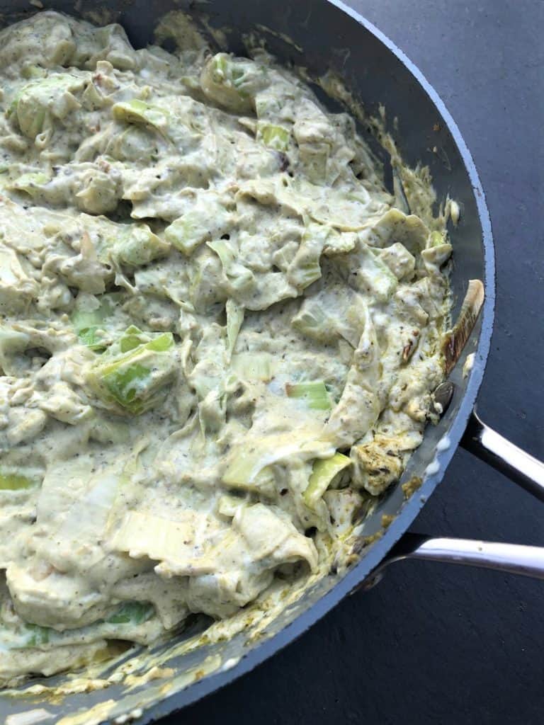 chicken and leeks mixed with cream cheese and pesto in a pan