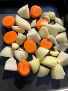 chopped onion and carrots in roasting tray