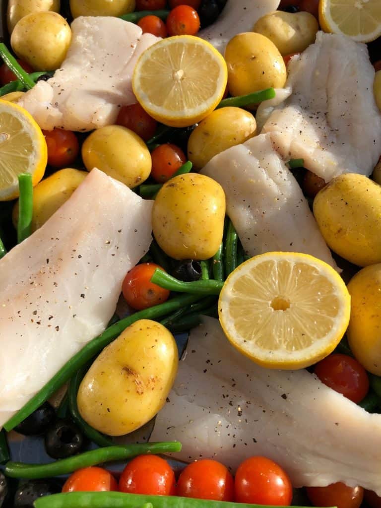 cod beans tomatoes potatoes lemon halves in a roasting tray