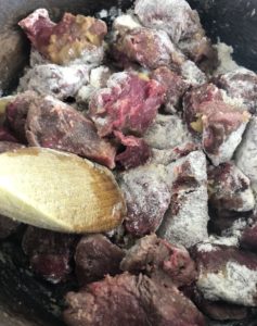 diced beef and flour frying in pan