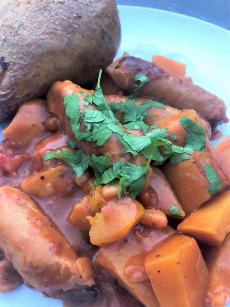 sausage and pumpkin casserole with jacket potato and fresh parsley
