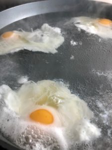 4 eggs poaching in pan