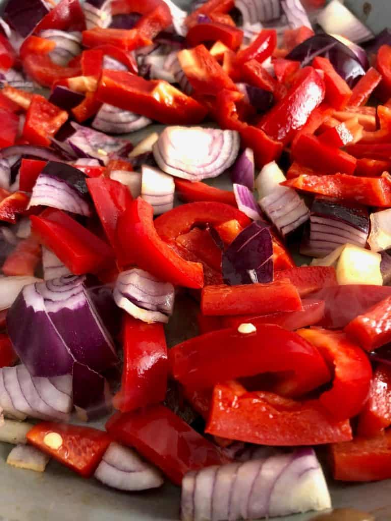 red onions and peppers frying in pan