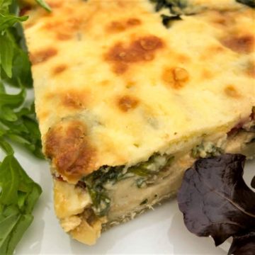 slice quiche on plate with salad