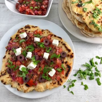 flatbread with salsa olives feta and stack flatbreads with parsley in background