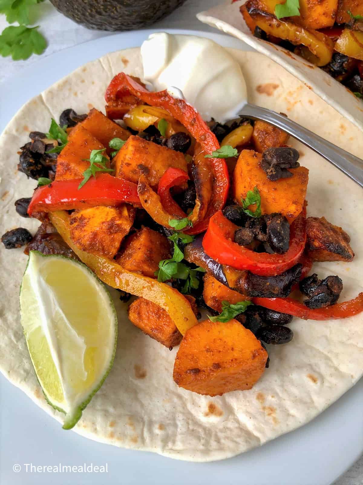 roasted vegetables on open tortilla with slice lime and spoonful soured cream