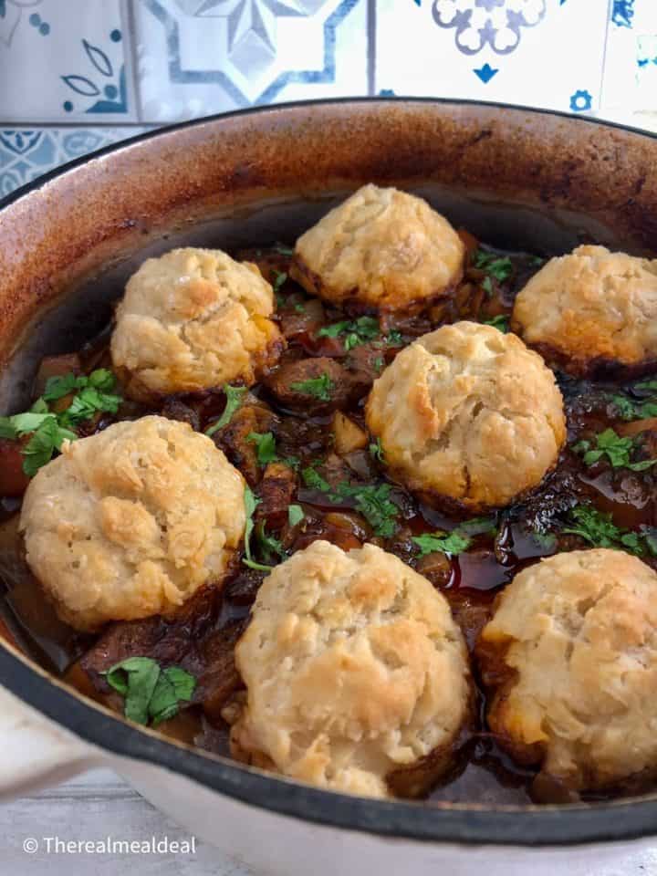 Beef Stew in casserole pot with sprinkling of parsley and dumplings