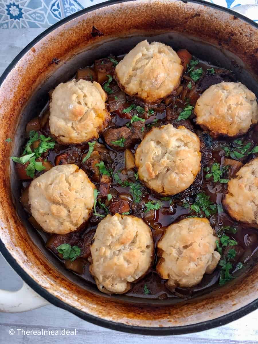 beed stew in casserole pot with 8 dumplings on top