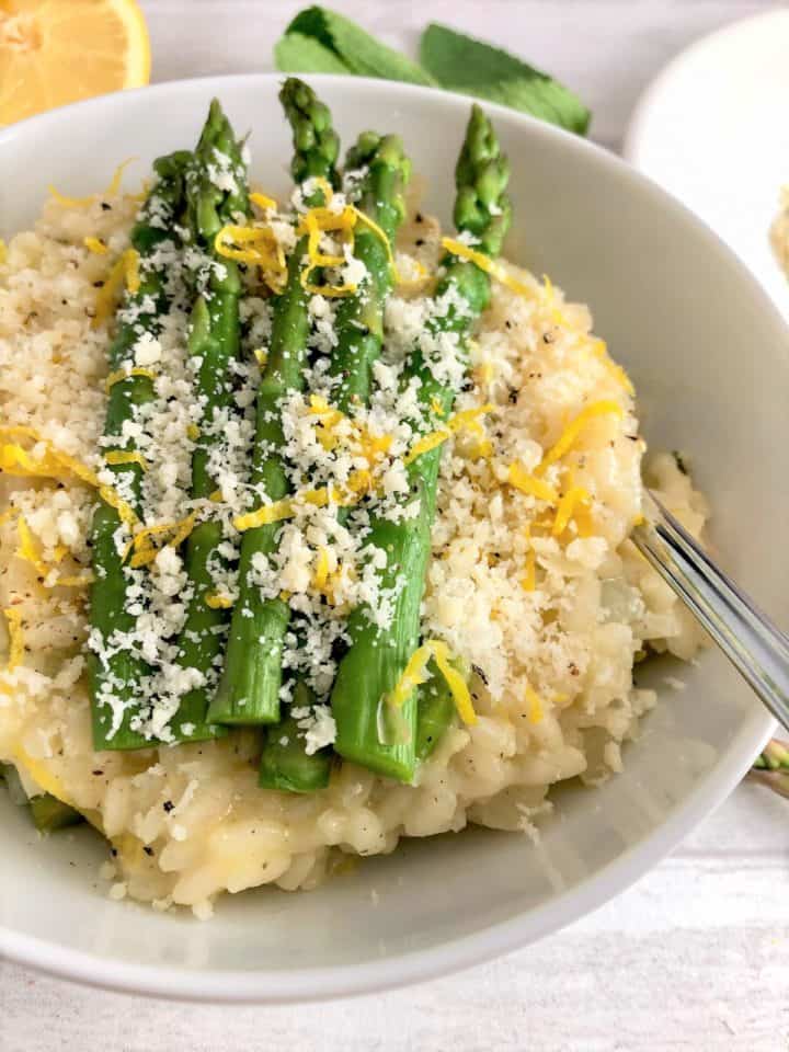 asparagus mint lemon risotto in bowl topped with lemon zest and parmesan cheese