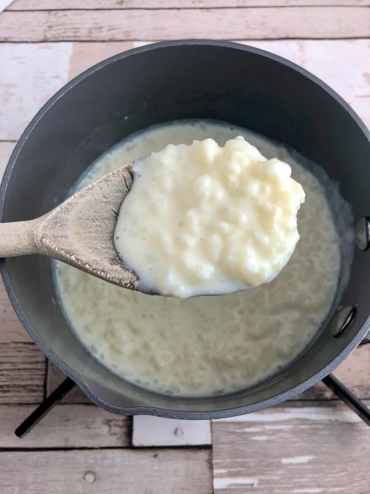 Rice pudding thickened in pan with wooden spoon