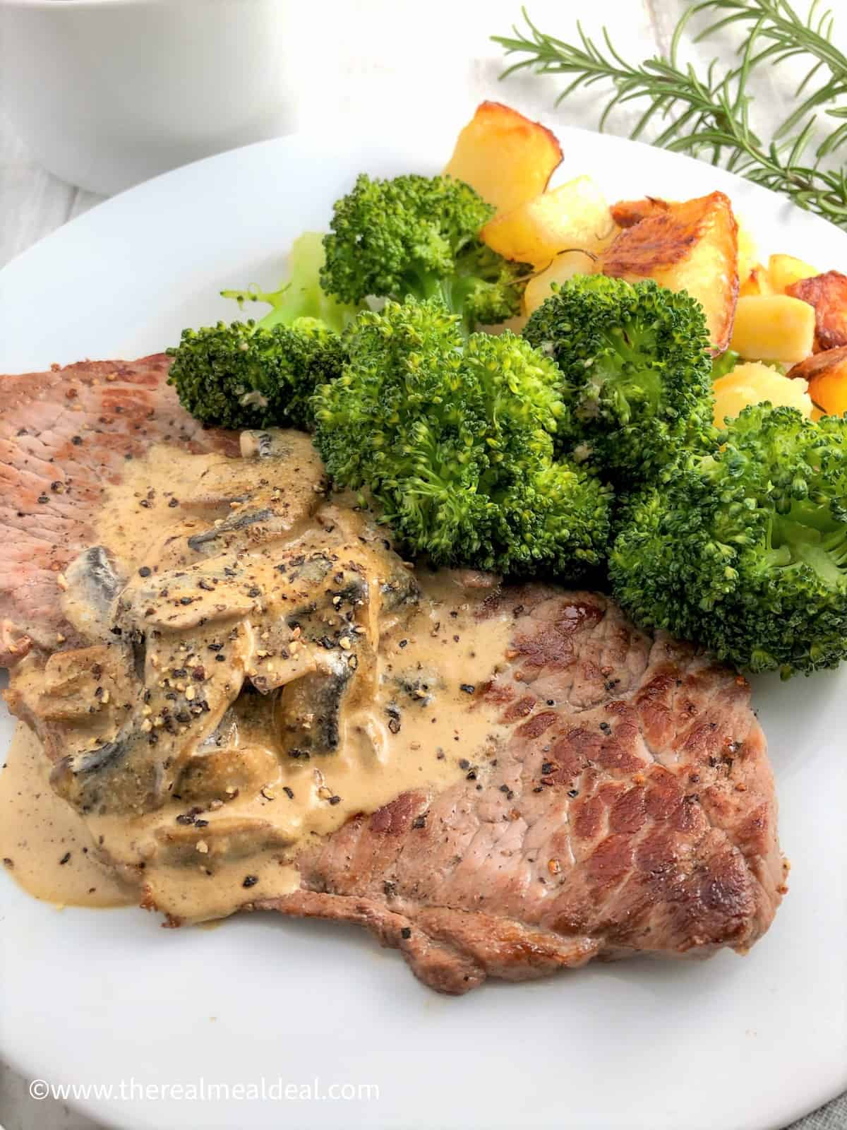 rose veal escalopes on plate with mushroom sauce and broccoli and roasted potatoes