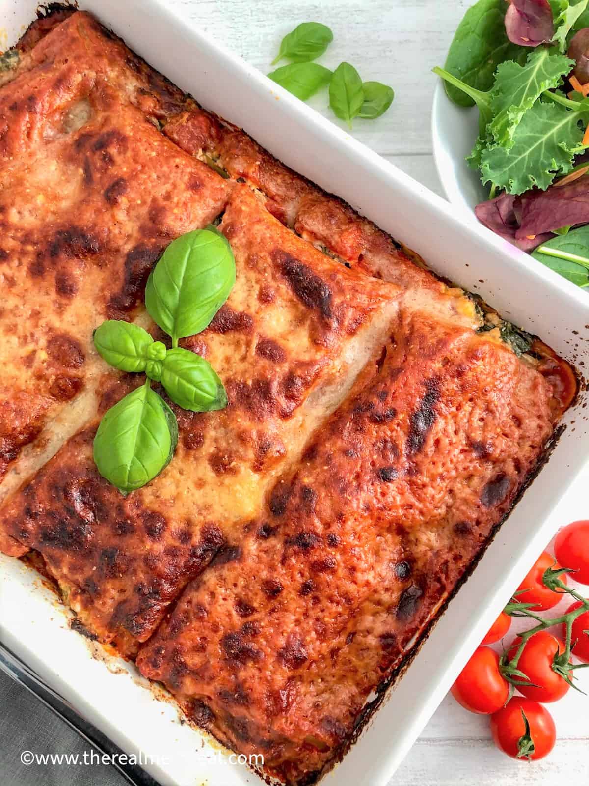 Spinach and Ricotta Lasagne baked in dish with cherry tomatoes and side salad