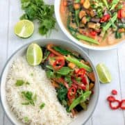 thai vegetable green curry in bowl with white rice. Second bowl behind with just curry topped with fresh coriander red chilli and slices lime