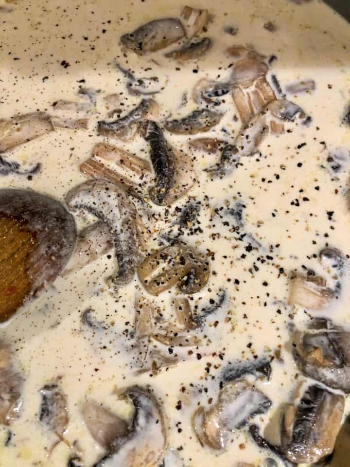 cream added to fried mushrooms in pan