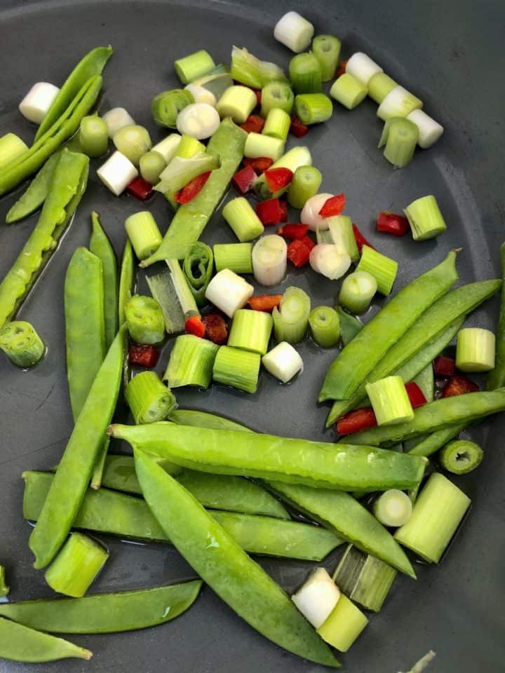 spring onions red chilli and mangetout frying in pan