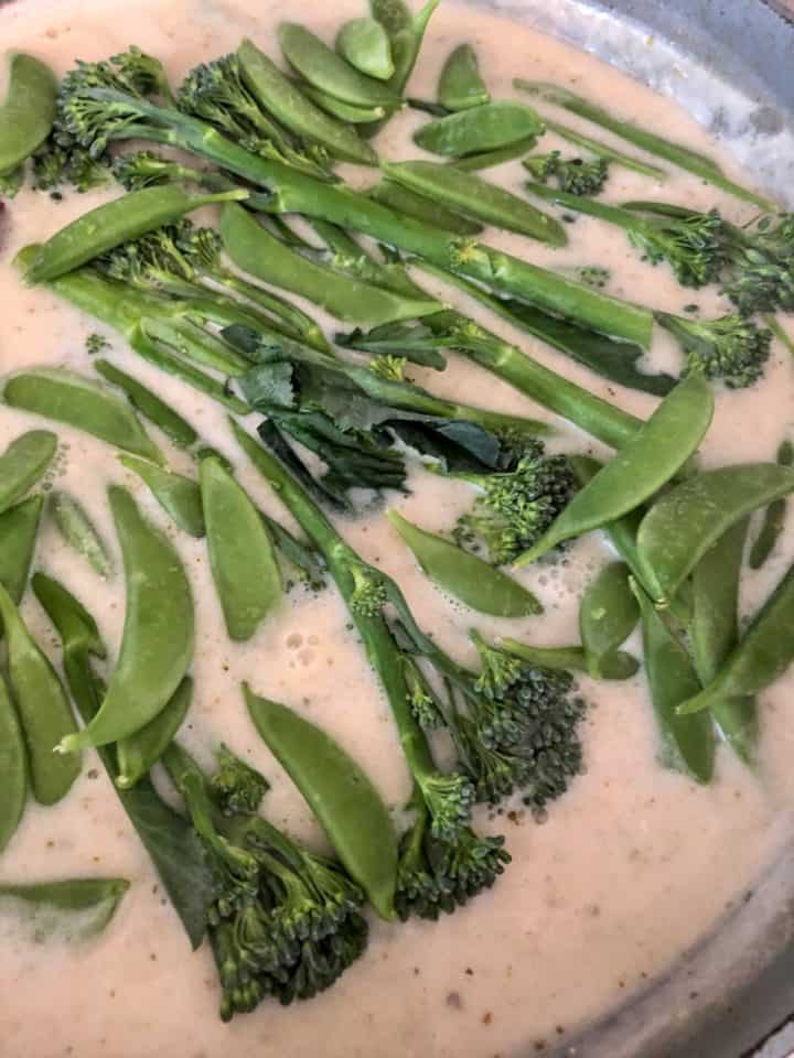 sugar snap peas and tenderstem broccoli simmering in thai green curry sauce with coconut milk