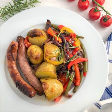 overhead view of sausage tray bake with mediterranean vegetables on plate