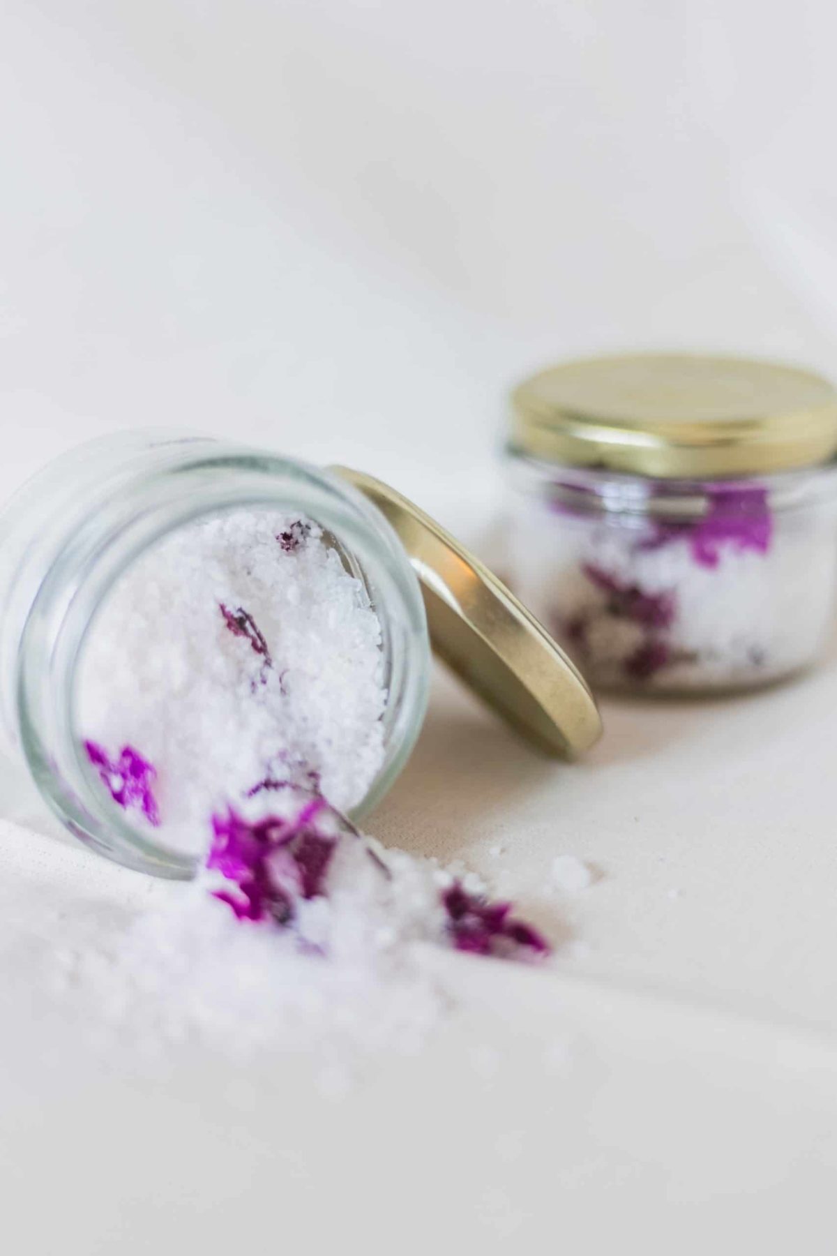 overtunred jar of bath salts containing salts and purple petals
