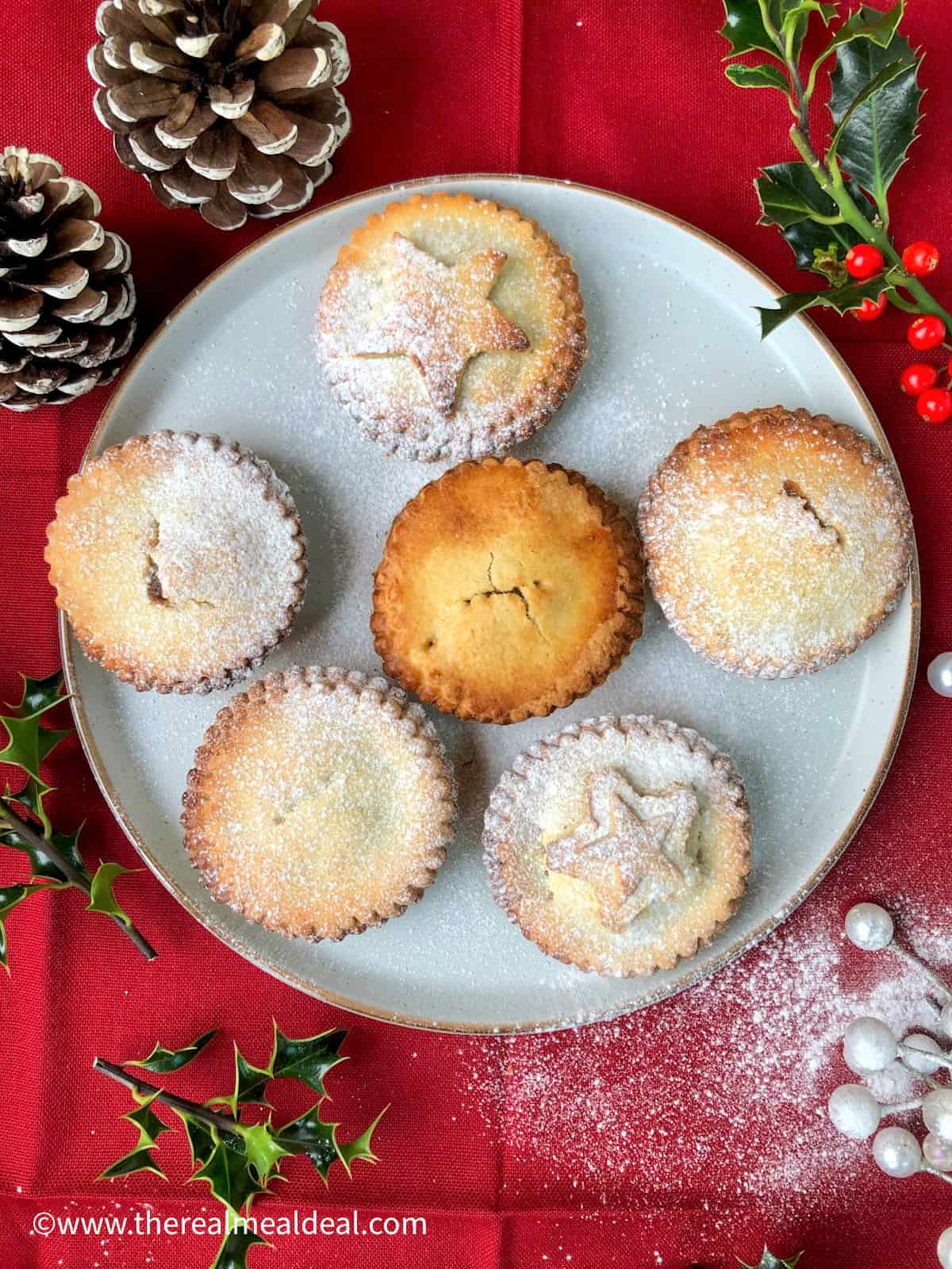 Decorated Mince pies on a plate with light dusting icing sugar