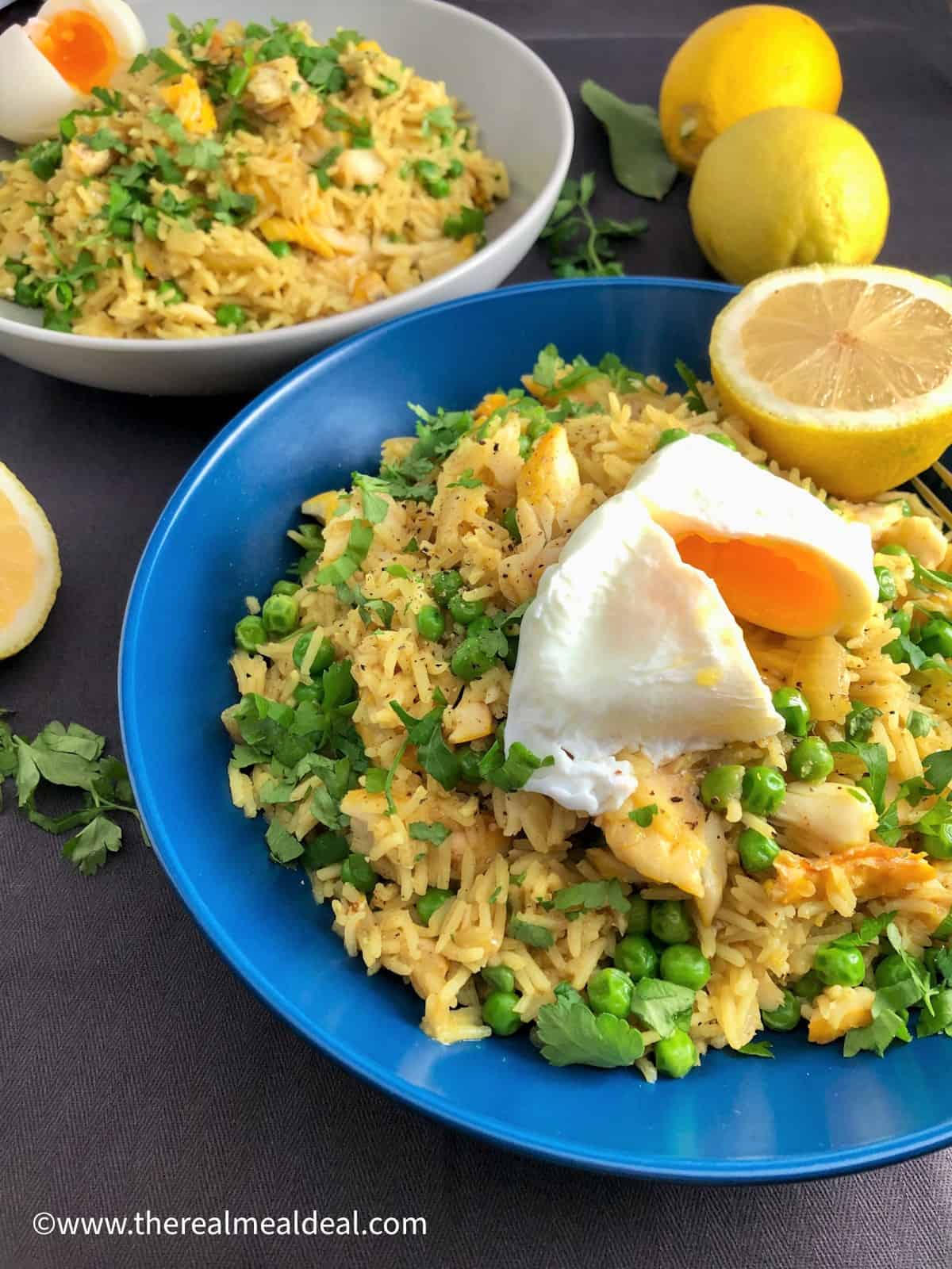 two bowls of kedgeree with poached egg and boiled egg topped with fresh parsley