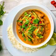 keralan fish curry in a bowl topped with fresh coriander leaves with side of rice and lime halves