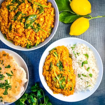 Lentil and Chickpea Curry with Spinach in bowl with rice, flatbread as side dish.