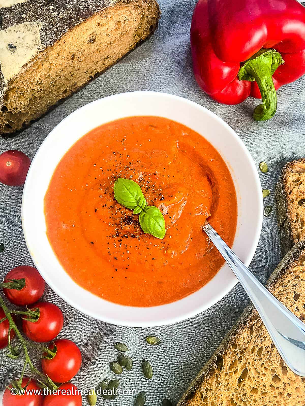 roasted red pepper and lentil soup in bowl garnished with fresh basil.