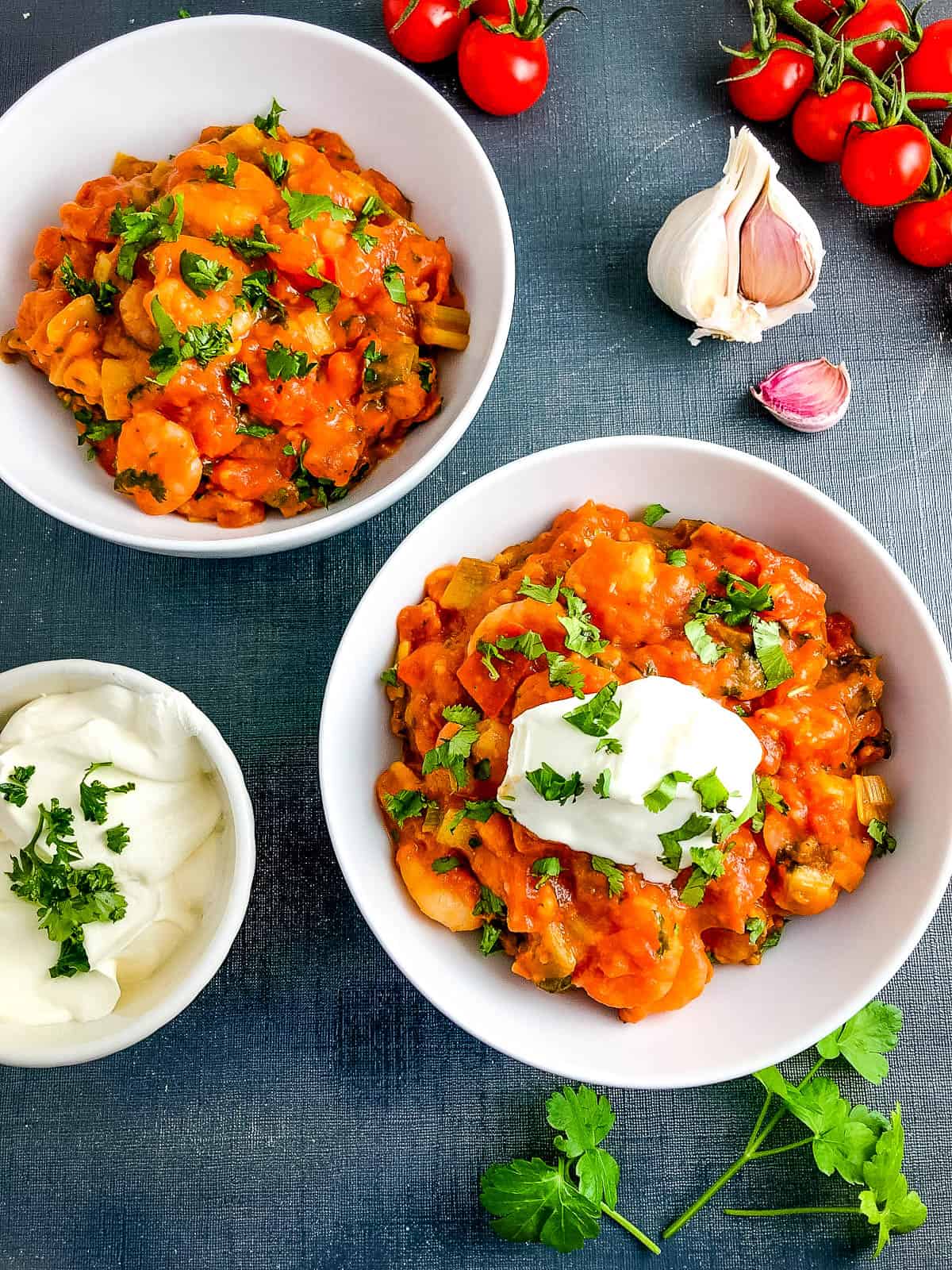 two bowls of garlic shrimp in tomato sauce topped with creme fraiche