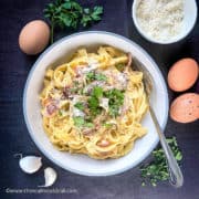 tagliatelle carbonara in bowl topped with parmesan and fresh parsley