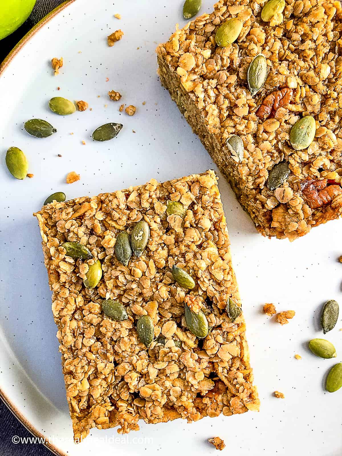 close up of apple and maple syrup flapjacks on plate with pumpkin seeds