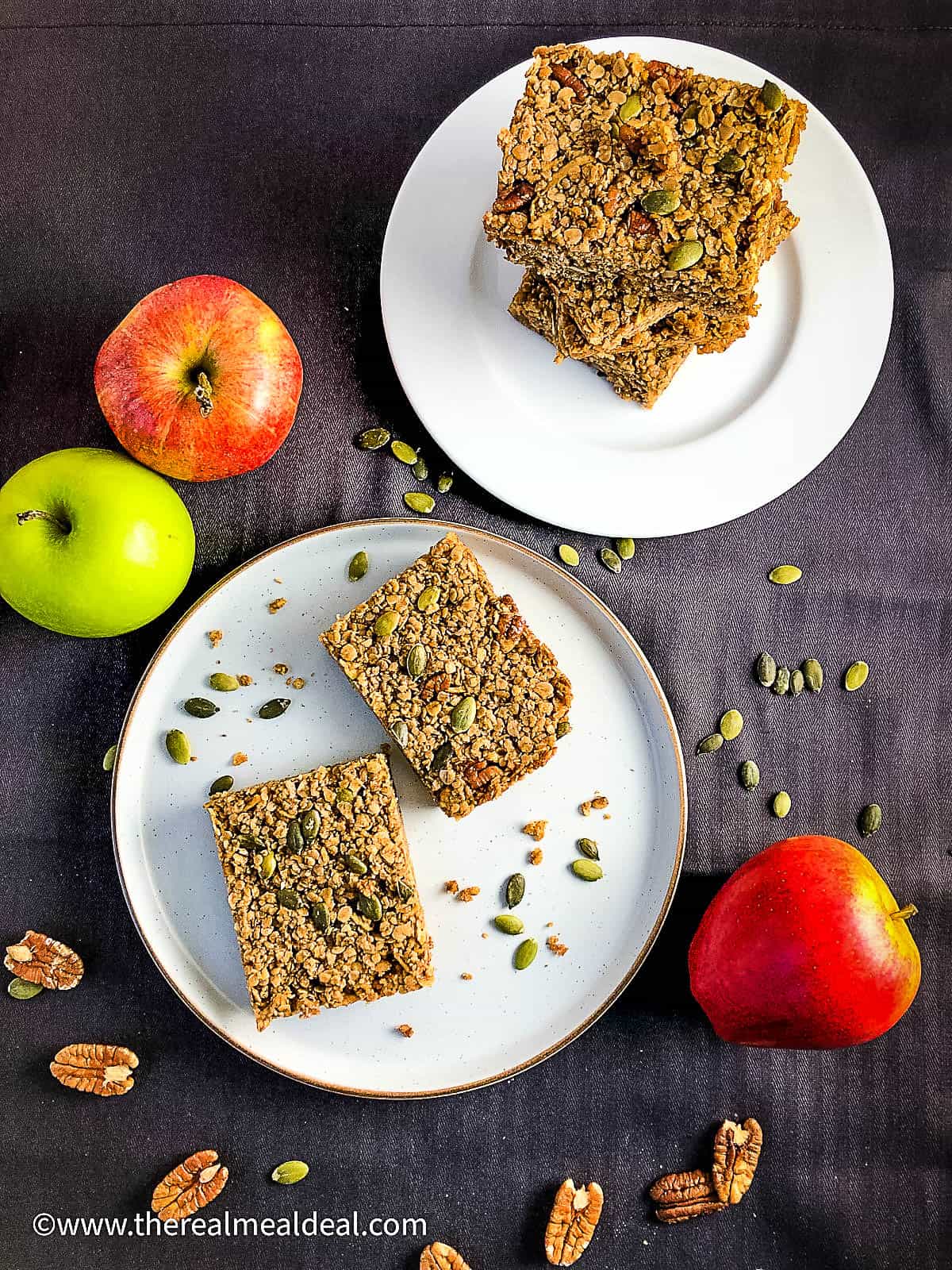 slices of vegan apple and maple syrup flapjack on plate surronded by whole apples and pecan nuts
