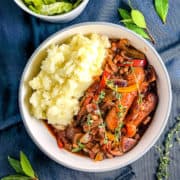 vegan sausage casserole with beans and side of mashed potato topped with fresh thyme