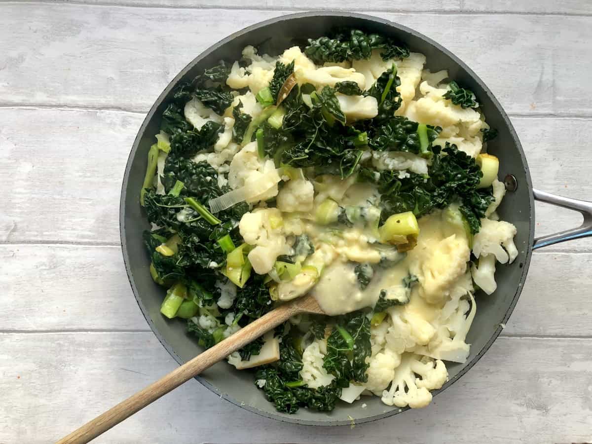 cauliflower leeks and kale in pan with cheese sauce stirred through