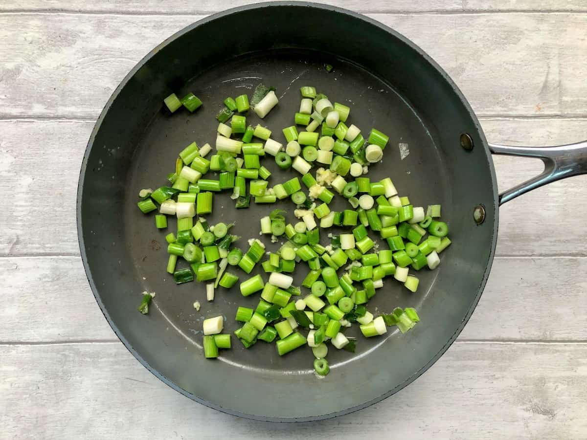spring onions and garlic frying in a pan