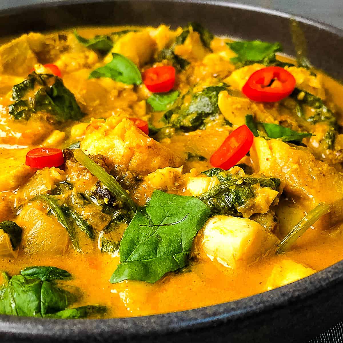 close up of fish korma in pan topped with fresh chilli and coriander leaves