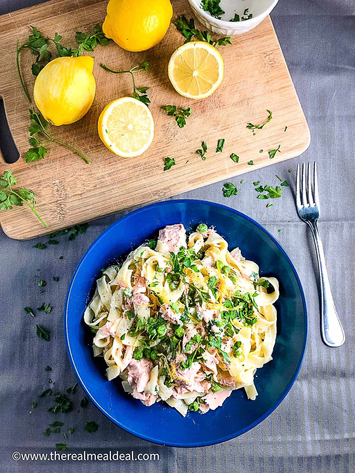bowl of creamy salmon pasta with creme fraiche no cream topped with parsley and lemon zest