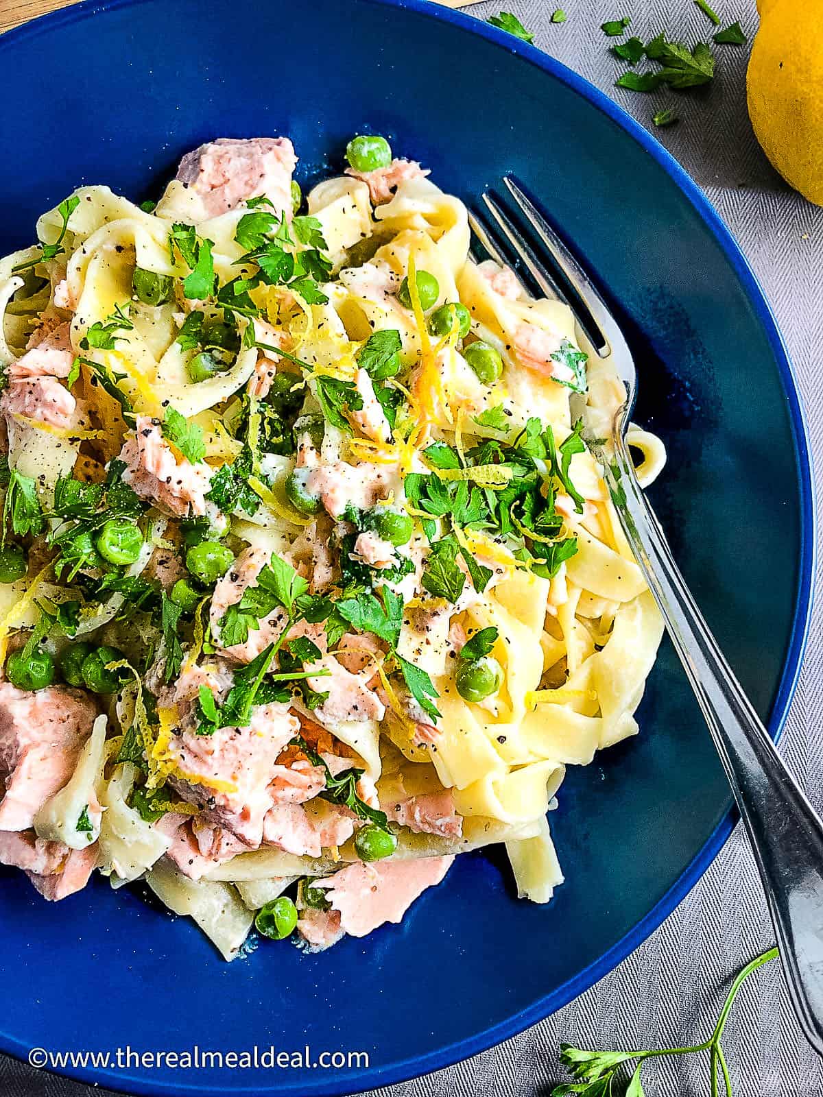 salmon pasta with creme fraiche in a bowl topped with fresh parsley