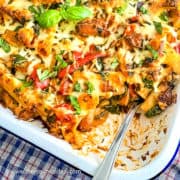 Creamy sausage and vegetable pasta baked in oven and portion removed.