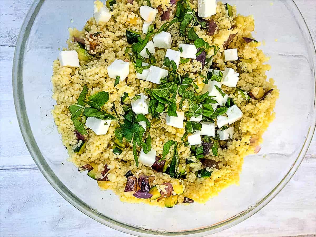 bowl of couscous with mediterranean vegetables diced feta cheese and fresh mint