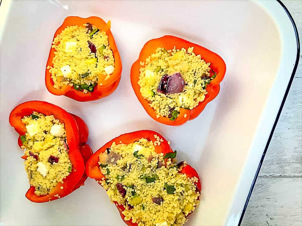 red pepper halves stuffed with mediterranean vegetables and feta cheese in baking dish