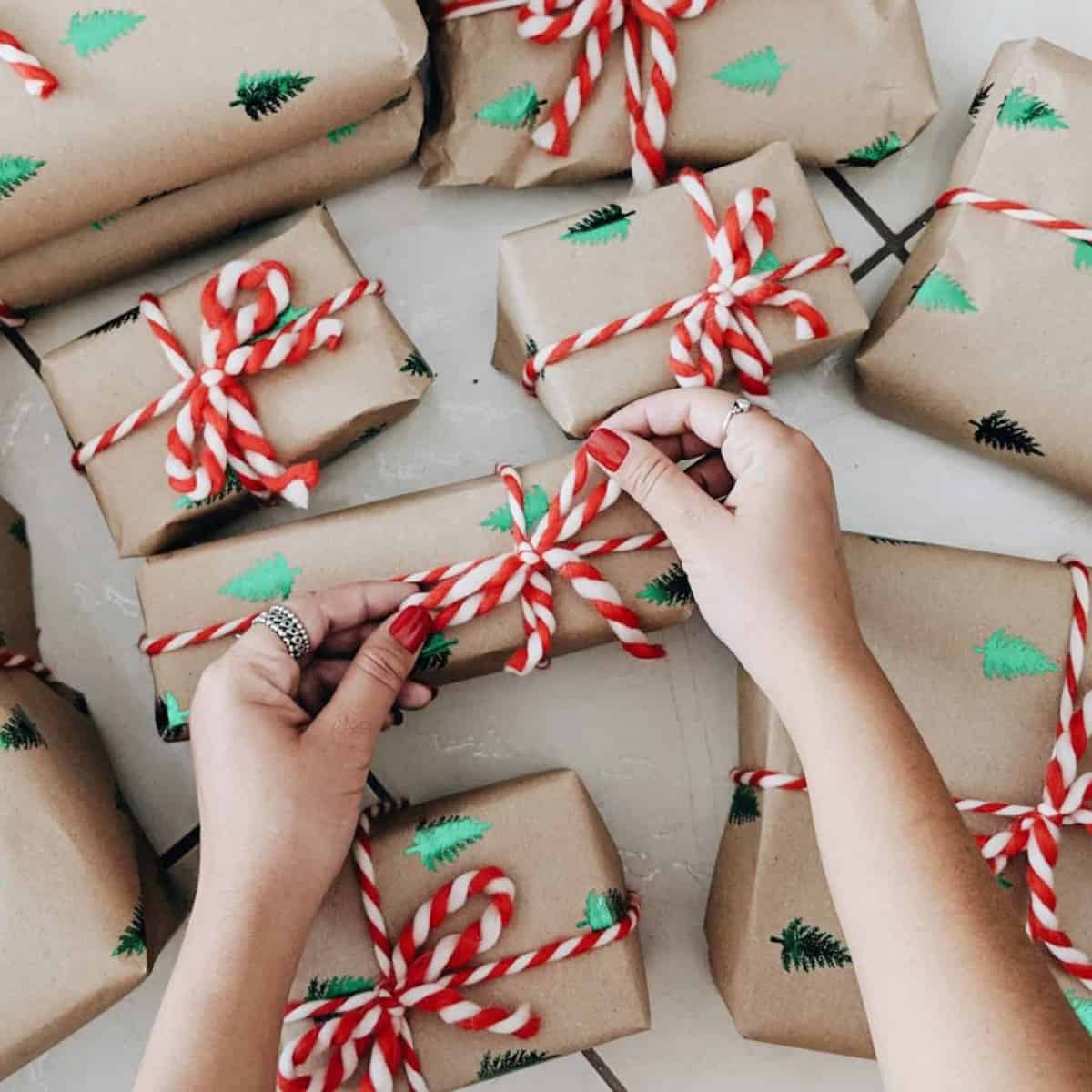 hands wrapping gifts in brown paper with red and white string
