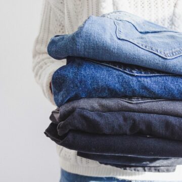 person holding a stack of folded pairs of jeans