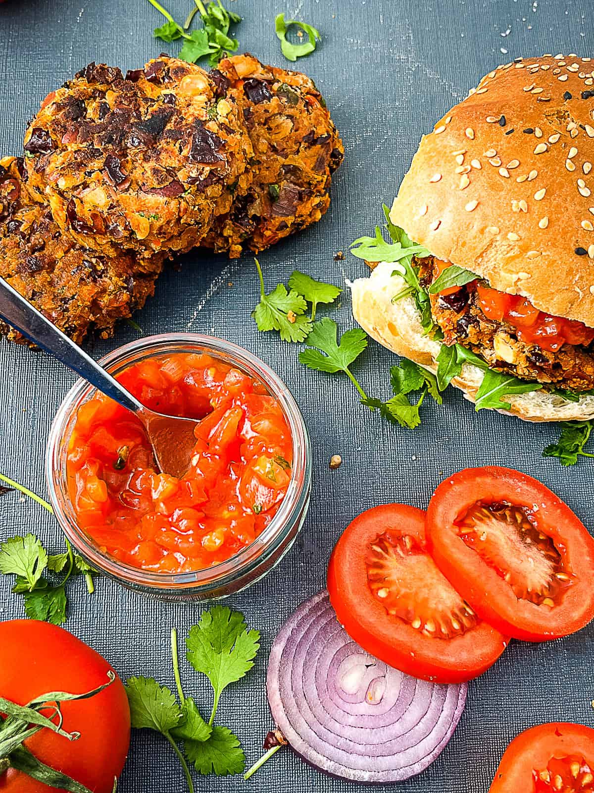 red kidney bean burgers with salsa, sliced tomato and red onion to side