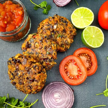 red kidney bean burgers with sides or salsa, limes sliced tomato and red onion