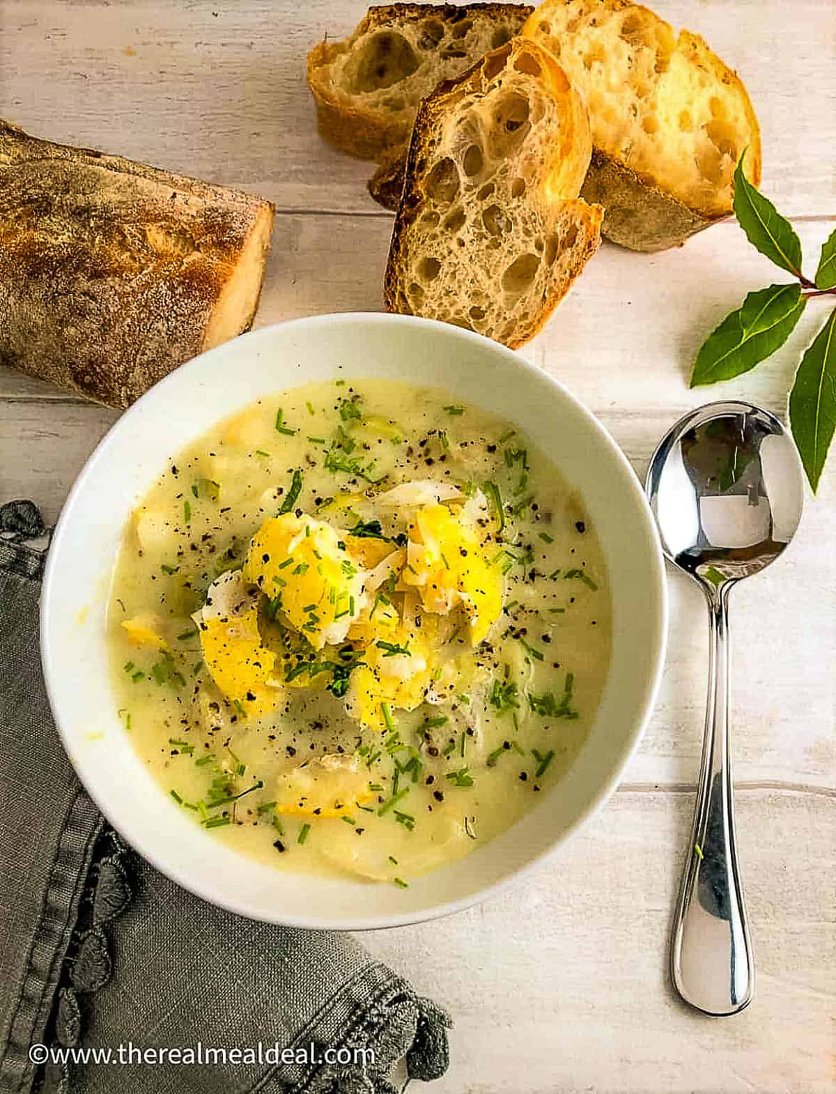 bowl of cullen sink soup topped with fresh chives with crusty bread on side