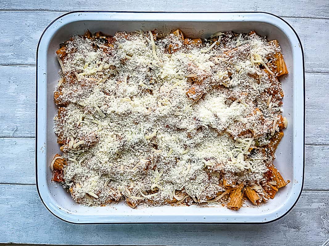 vegetable and pesto pasta bake assembled ready to be baked topped with cheese