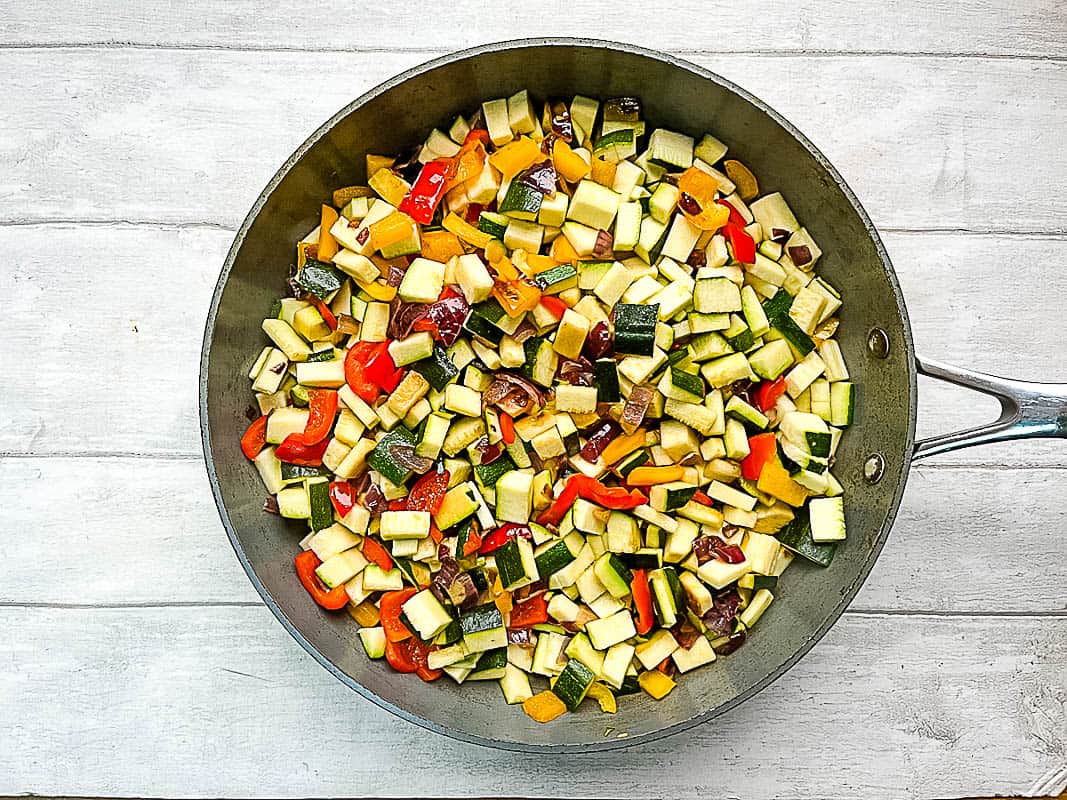 red onion, red and yellow bell pepper and courgette or zucchini frying in pan