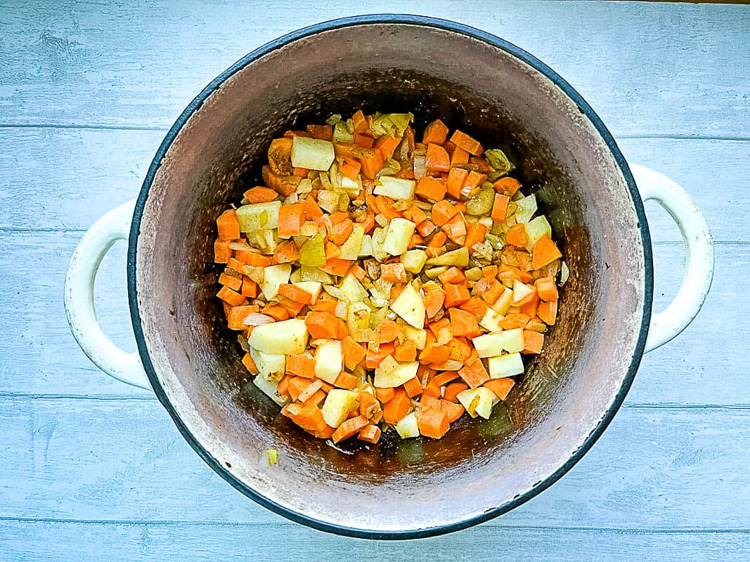 diced carrot and potato added to onions in pan