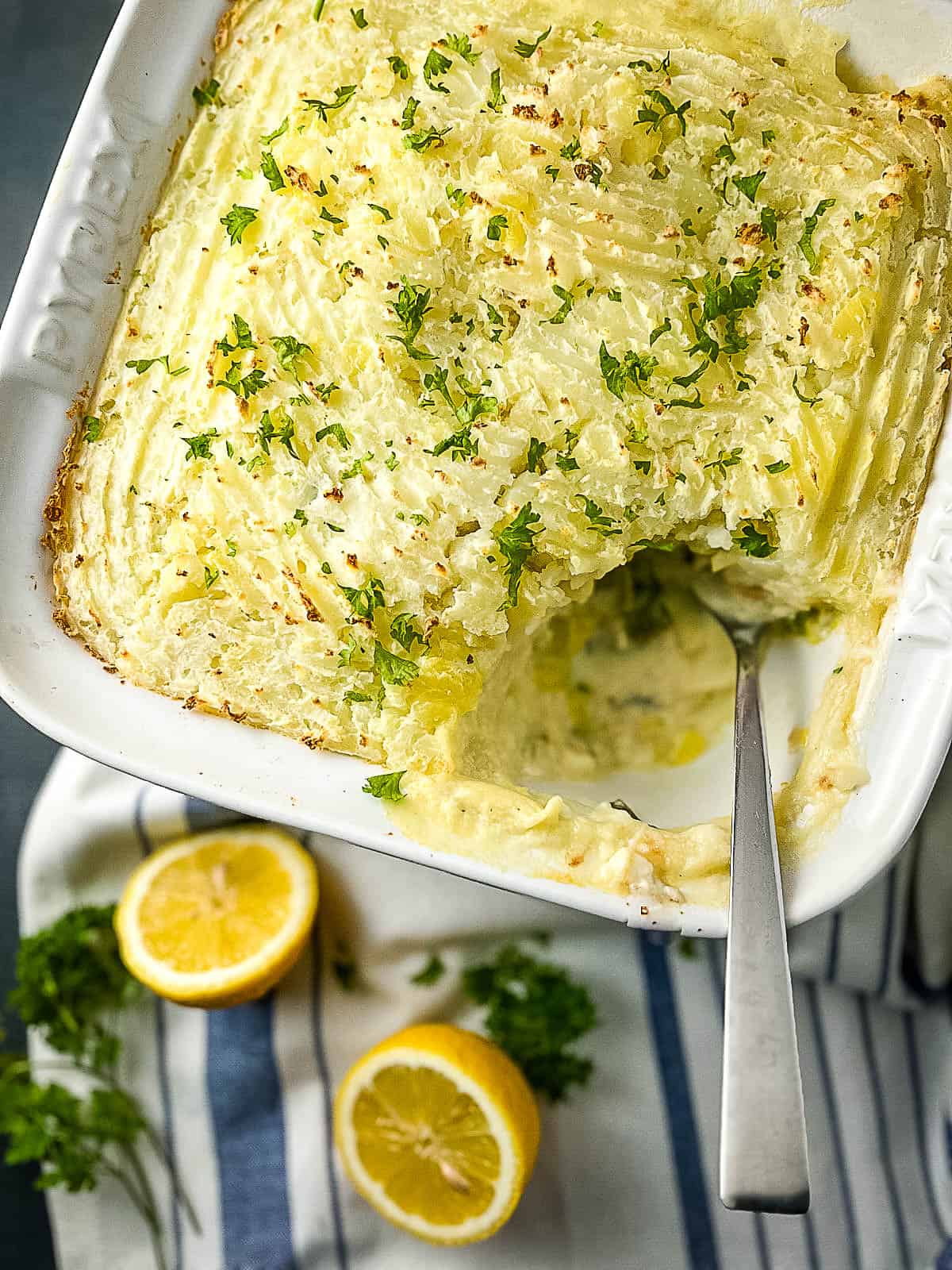 baked fish pie showing portion removed and topped with fresh parsley