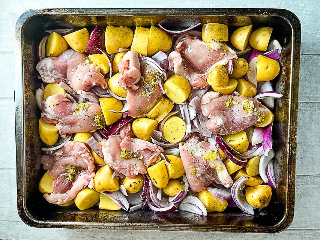 boneless chicken thighs baby potatoes red onion and lemon and thyme marinade in roasting tray